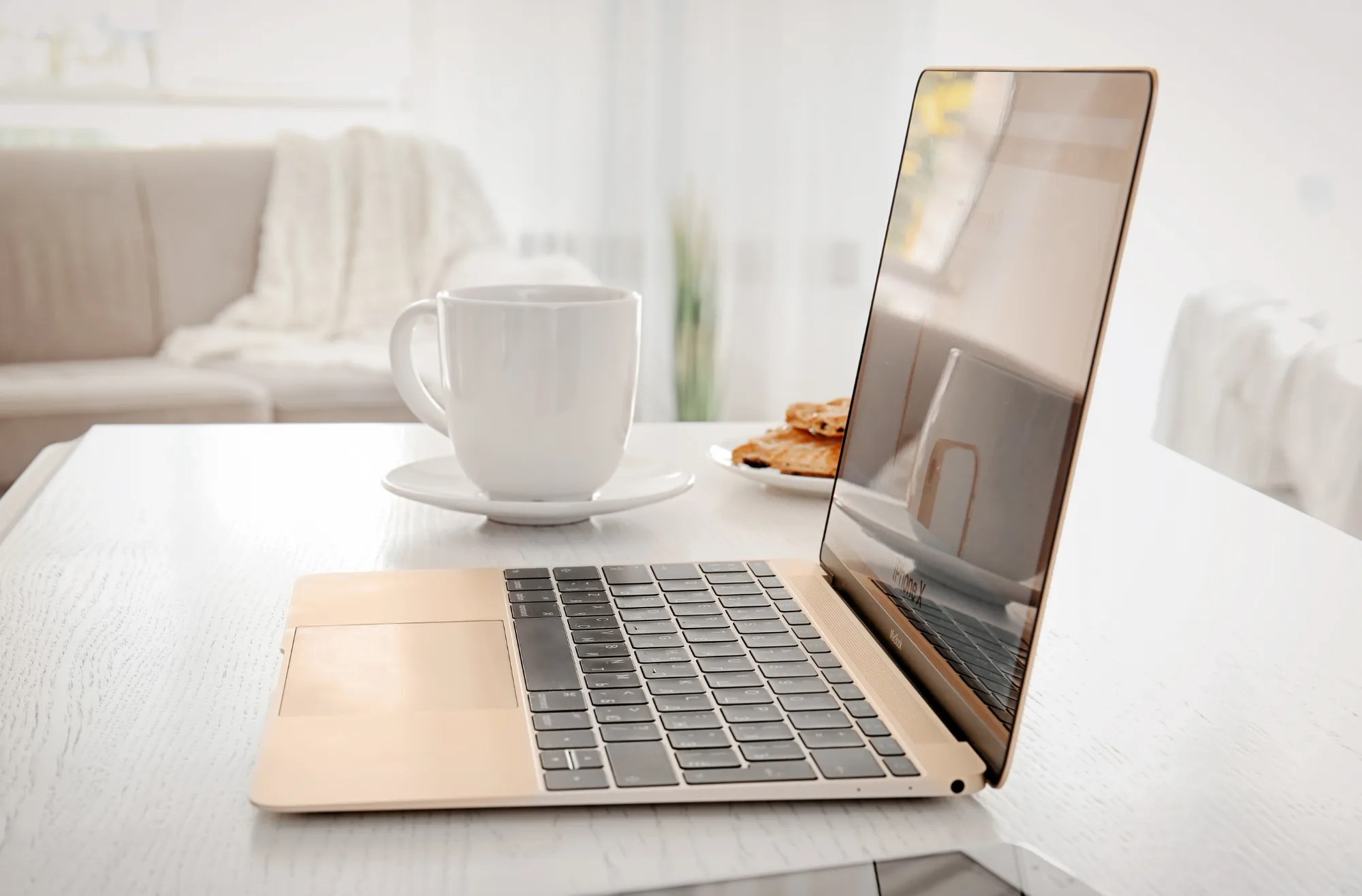 Rose gold MacBook on a white table in a white room.